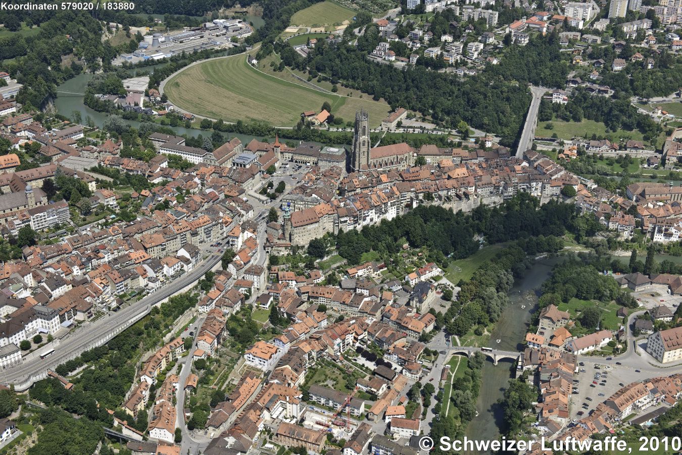 Fribourg, Überblick Altstadt mit Kathedrale und im Vordergrund mit Brücke: Neuveville/Neustadt. Im Hintergrund rechts: Zähringerbrücke nach 'Schönberg'. (N: linke obere Bildecke). Bildmitte: Rathaus mit Murtenlinde. Grosses Gebäude unten rechts beim Parkplatz: Kornhaus, heute Archäologischer Dienst. - Industriekomplex links oben: ARA